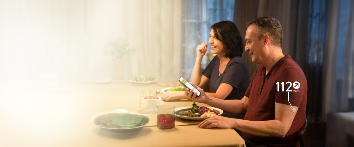 Man sitting at the dinner table checking his blood glucose on a smartphone