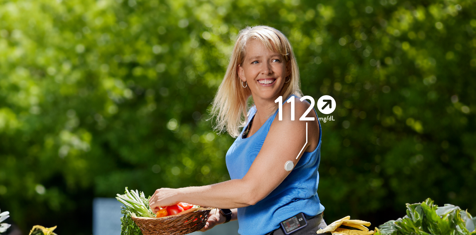 Woman collecting vegetables from a garden while wearing a FreeStyle Libre 2 Plus sensor