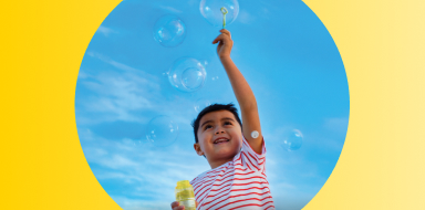 Child playing with bubbles while wearing a FreeStyle Libre 3 Plus sensor