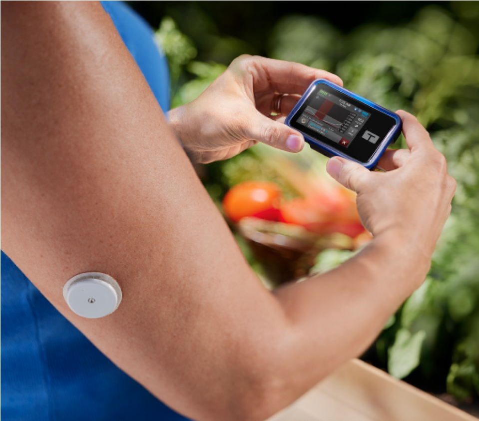Person wearing a FreeStyle Libre 2 Plus sensor and checking the Tandem t:slim X2 insulin pump