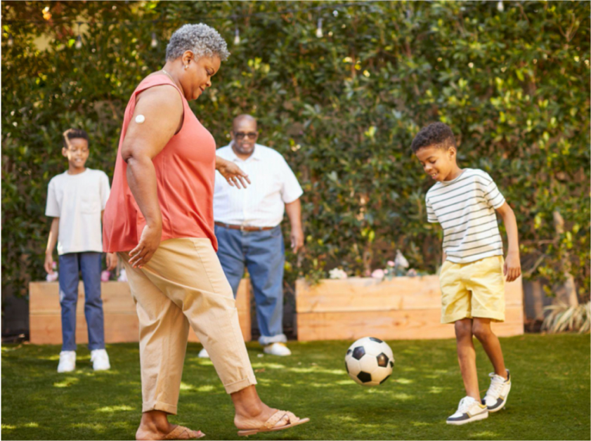 Woman kicking a soccer ball with a child while wearing a FreeStyle Libre 2 sensor