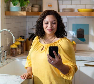 Woman in a kitchen checking her blood glucose on a mobile device