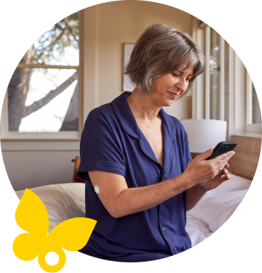 Woman wearing a FreeStyle Libre sensor checking blood glucose on her smartphone